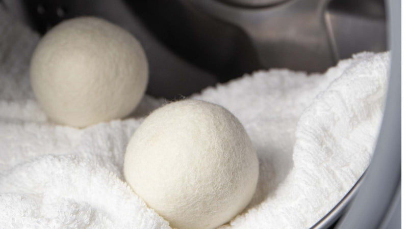 Two wool dryer balls and a white towel in the dryer drum—Do dryer balls damage fabric?