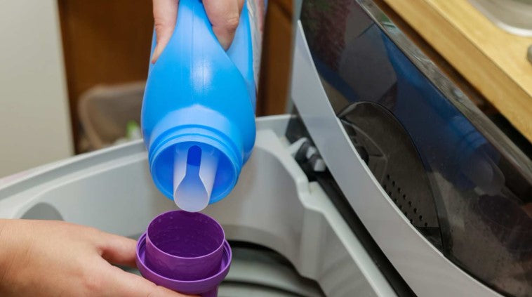 Woman puts fabric softener into the washing machine—Are there toxic chemicals in fabric softeners?